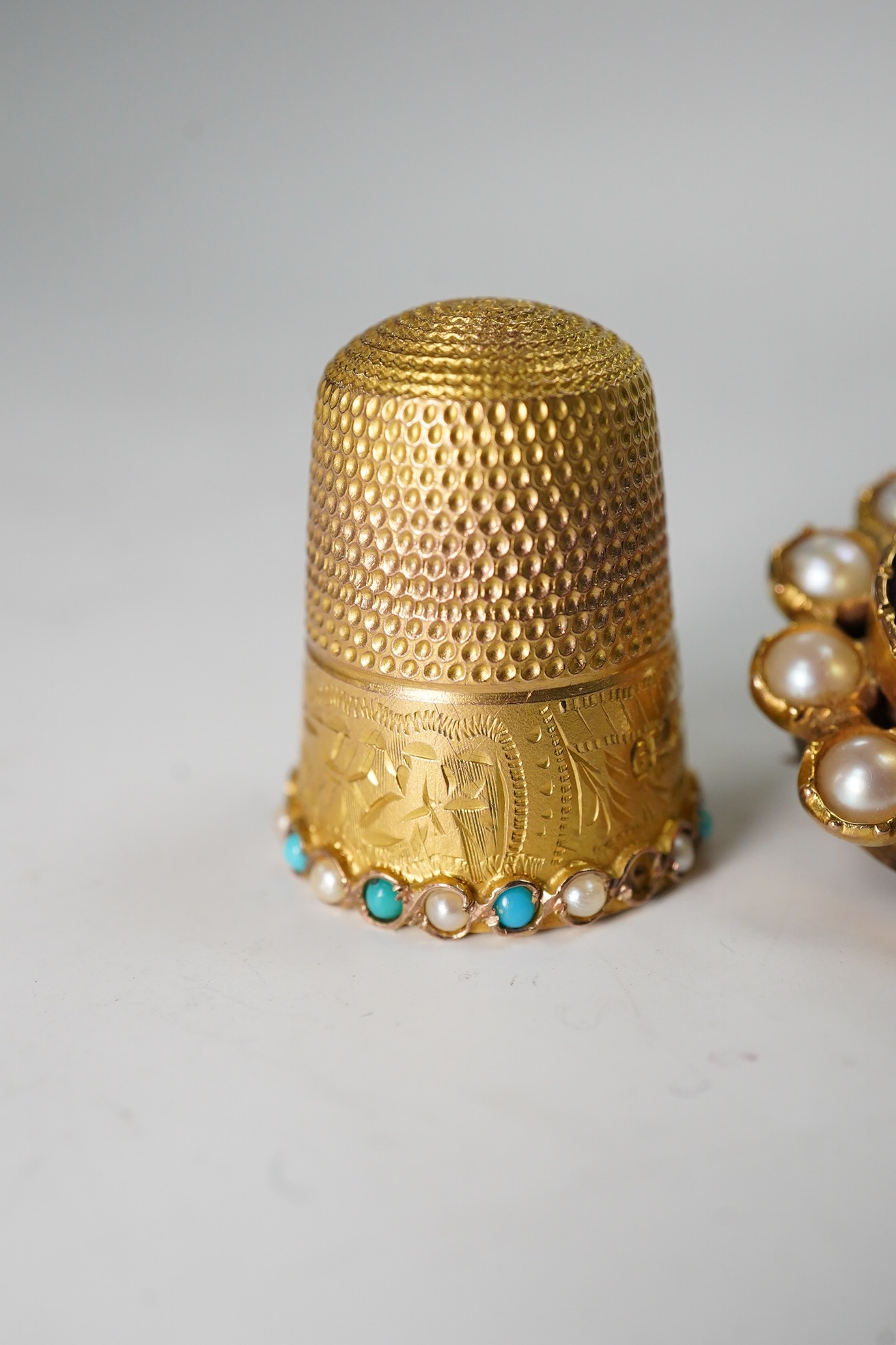A George V 9ct gold, turquoise and seed pearl set thimble, 5.9 grams, and an amethyst and split pearl set yellow metal clasp, converted to a brooch. Condition - poor to fair